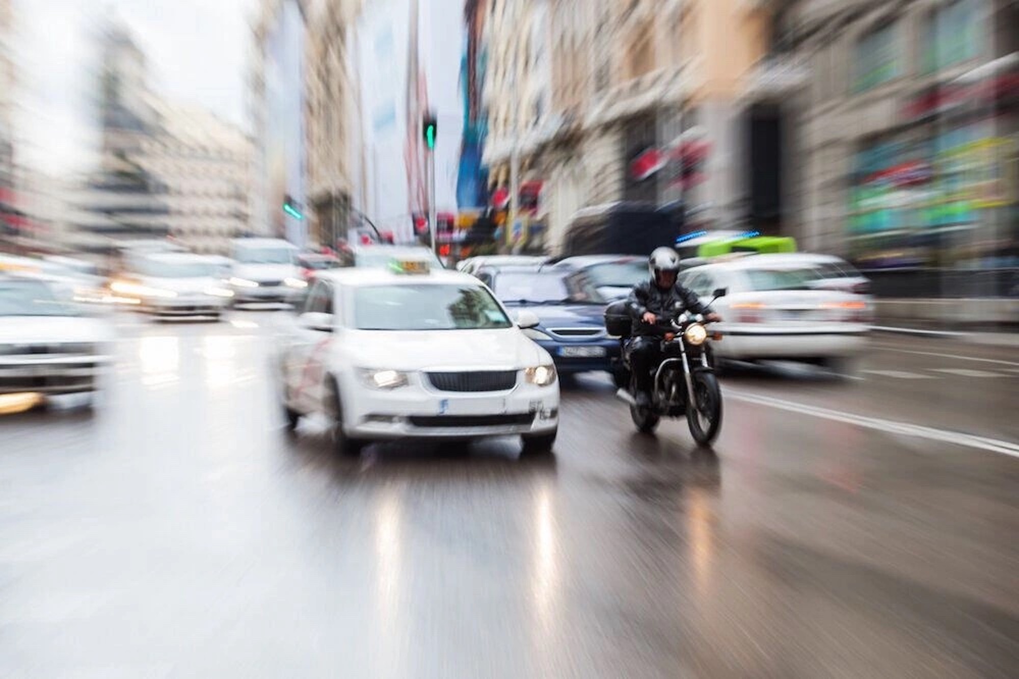 A car and a motorcyclist on a rainy Street. Photo courtesy of Kraft & Associates, PC