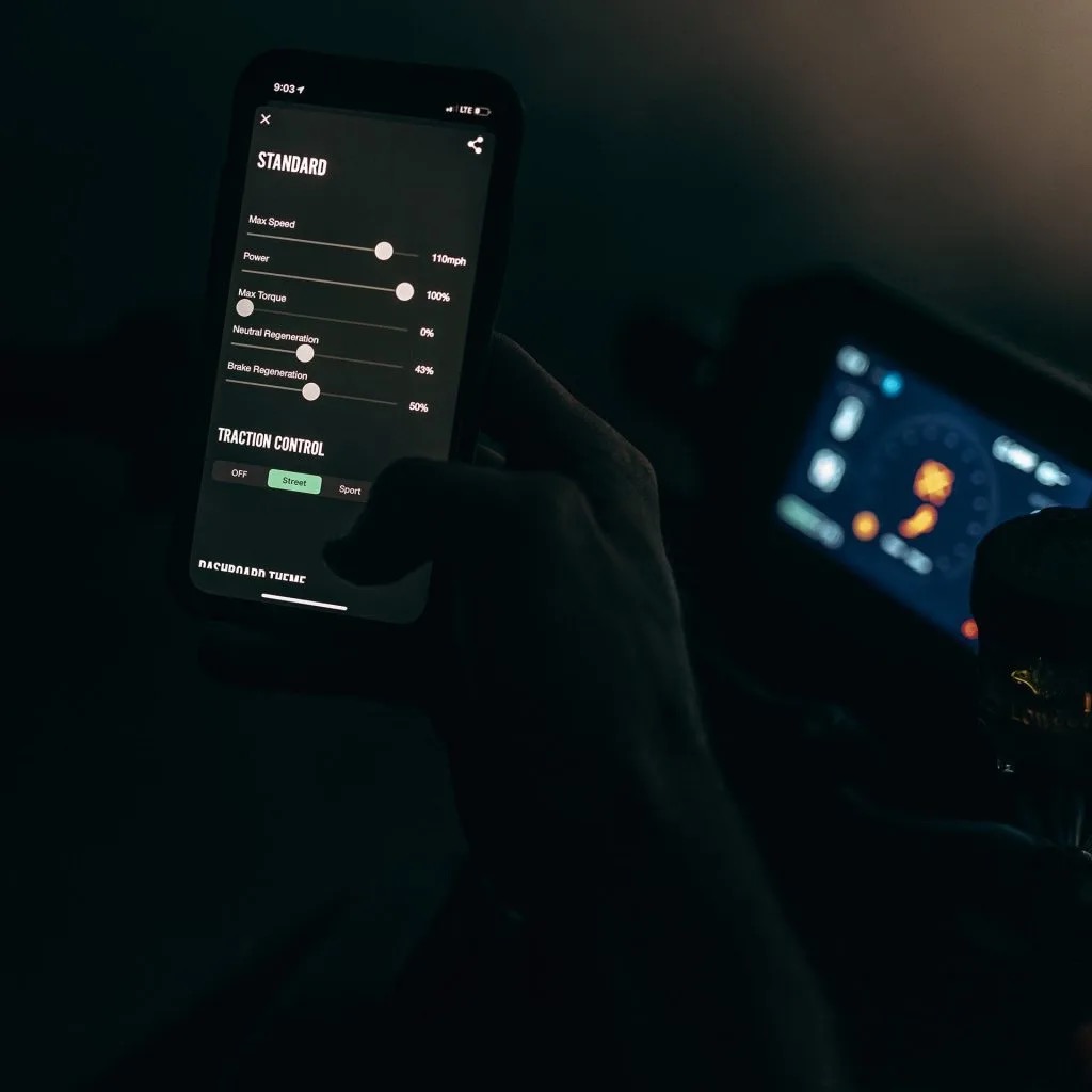 A phone held in front of a motorcycle screen. Media sourced from MotorBiscuit.