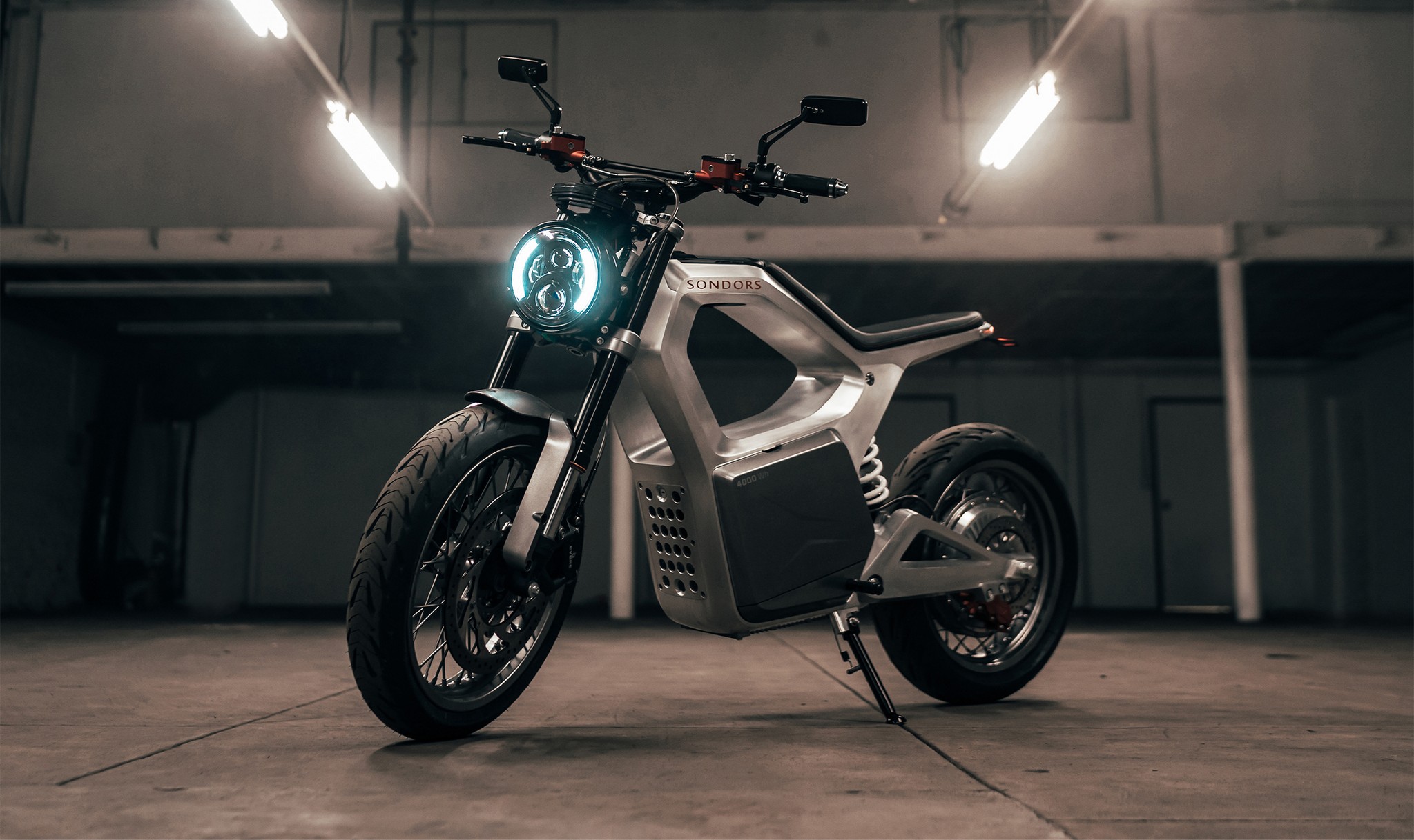 Sondors Metacycle electric motorbike parked stationary on kickstand in well-lit warehouse