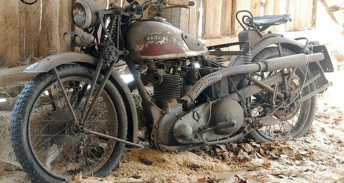 an old Ariel motorcycle sitting in a barn waiting to be repaired