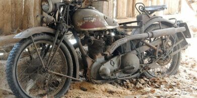 an old Ariel motorcycle sitting in a barn waiting to be repaired