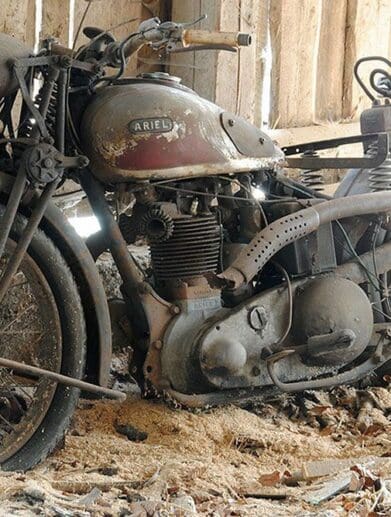 an old Ariel motorcycle sitting in a barn waiting to be repaired