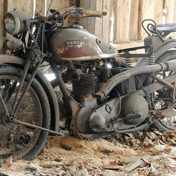 an old Ariel motorcycle sitting in a barn waiting to be repaired