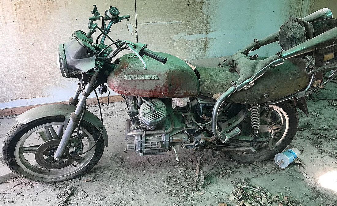 an old Honda CX motorcycle sitting in a barn waiting to be repaired