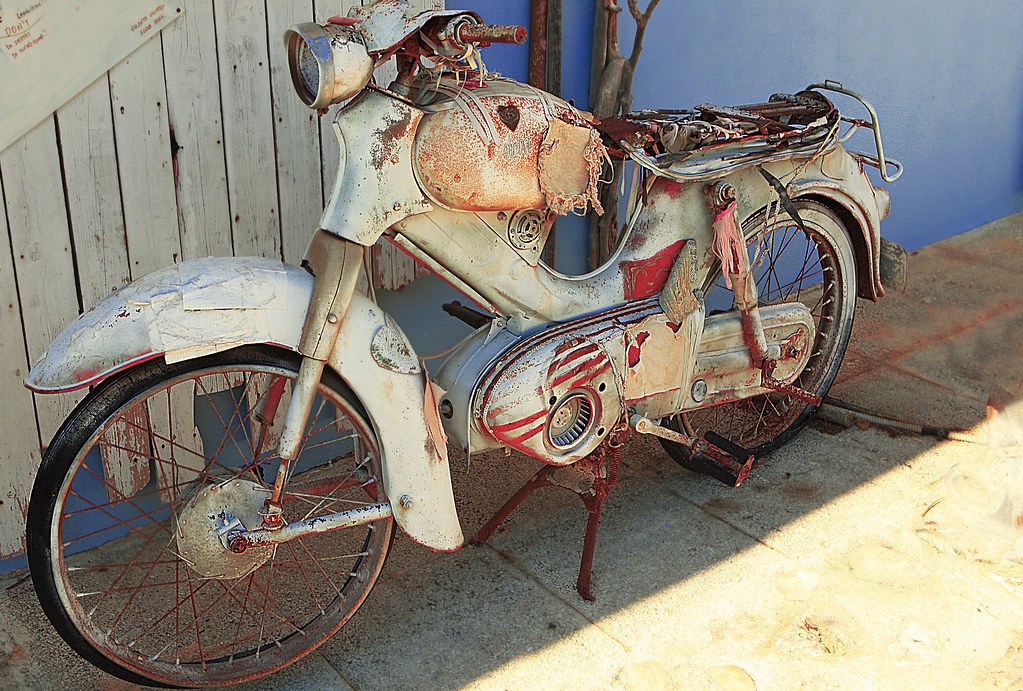 an old moped bike sitting outside waiting to be repaired