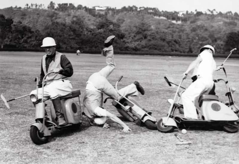 three men bumbling about in a match of scooter polo. Media sourced from Bygonely.