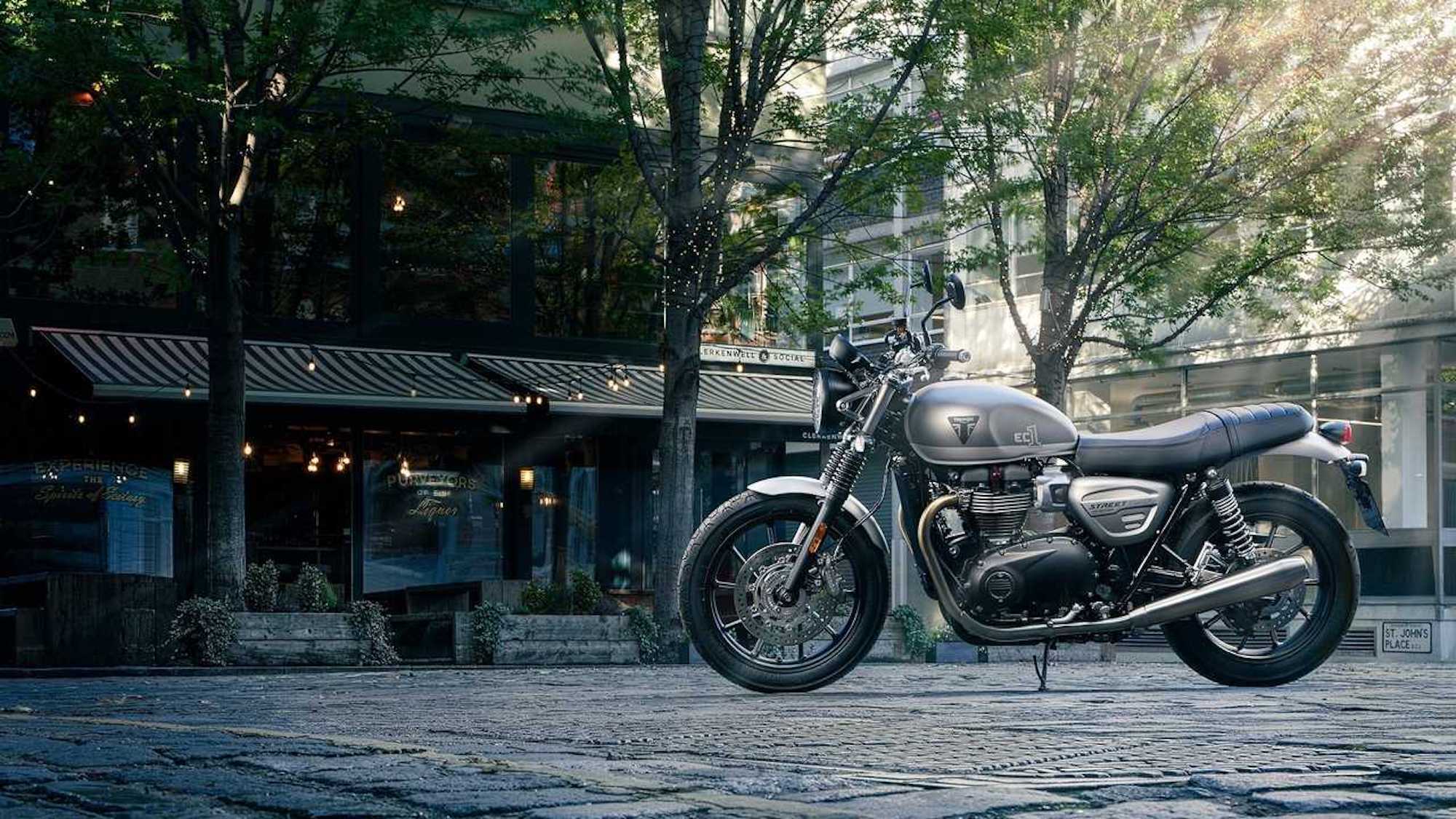 A triumph motorcycle parked next to a building in the shade.