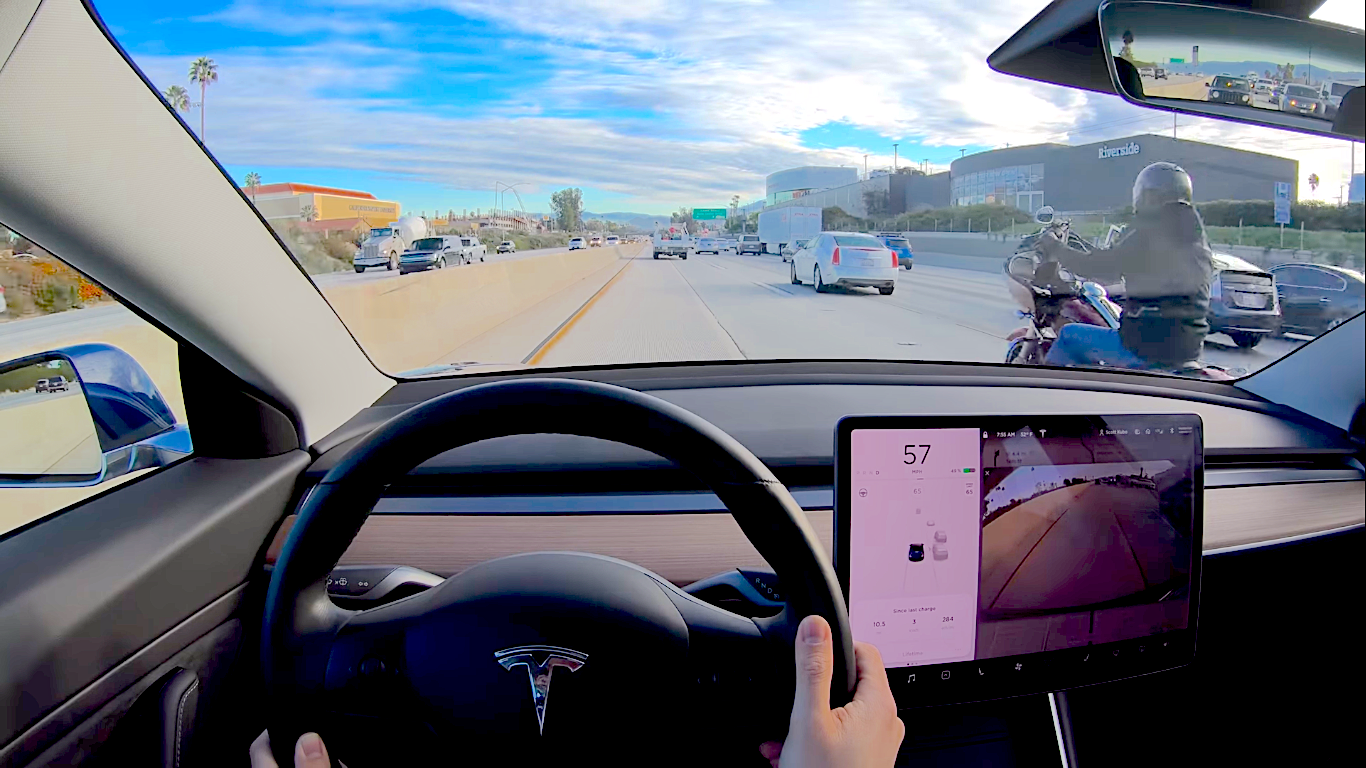 The inside of a Tesla, with a motorcyclist about to change lanes. Media sourced from VisorDown.