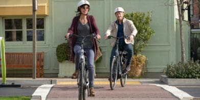 Two casually dressed riders, a man and a woman, in the bike lane on eBikes.