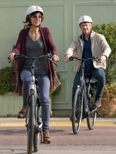 Two casually dressed riders, a man and a woman, in the bike lane on eBikes.