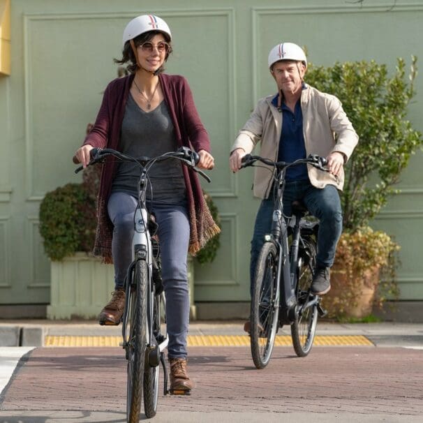 Two casually dressed riders, a man and a woman, in the bike lane on eBikes.