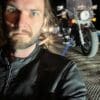 Author looking annoyed as motorcycle is lifted onto flatbed truck in background