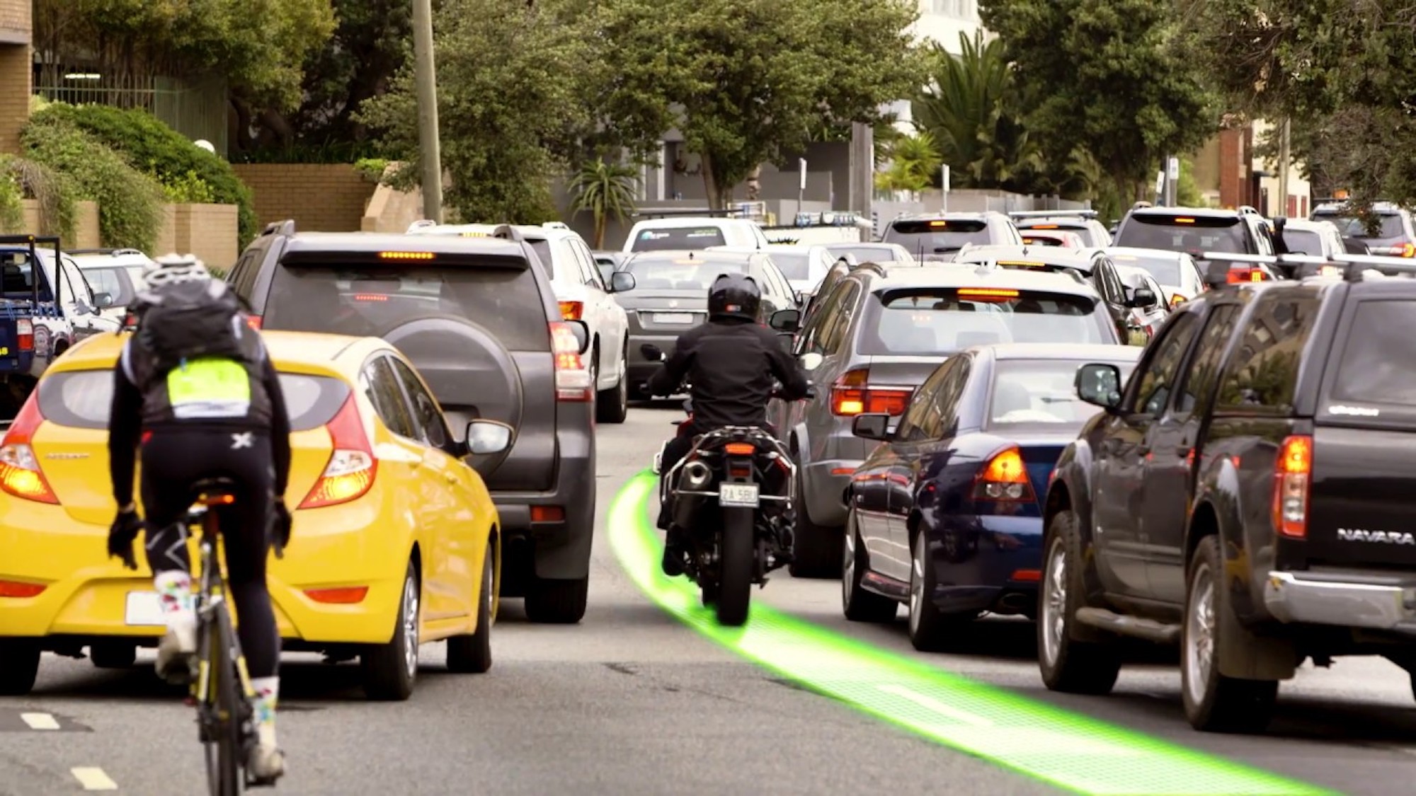 A rider lane filtering as cars wait at a stopped light. Media sourced from Youtube.