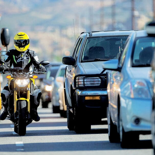 A rider lane filtering as cars wait at a stopped light. Media sourced from Rider Magazine.