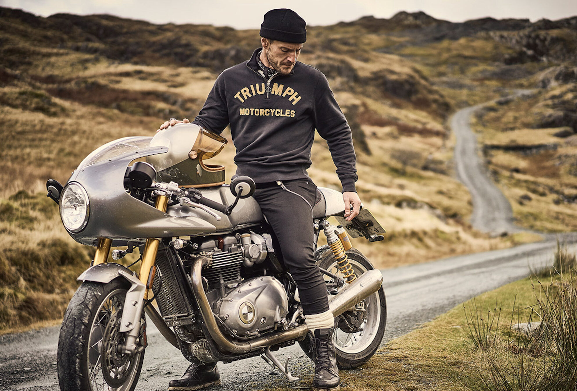 A male model astride a Triumph motorcycle. Media sourced from WE ARE MERCI.