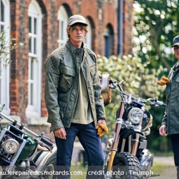 A view of two riders featuring gear and clothing from Triumph Motorcycles, next to Triumph motorcycles and a red-bricked building. Media sourced from the Coolector.