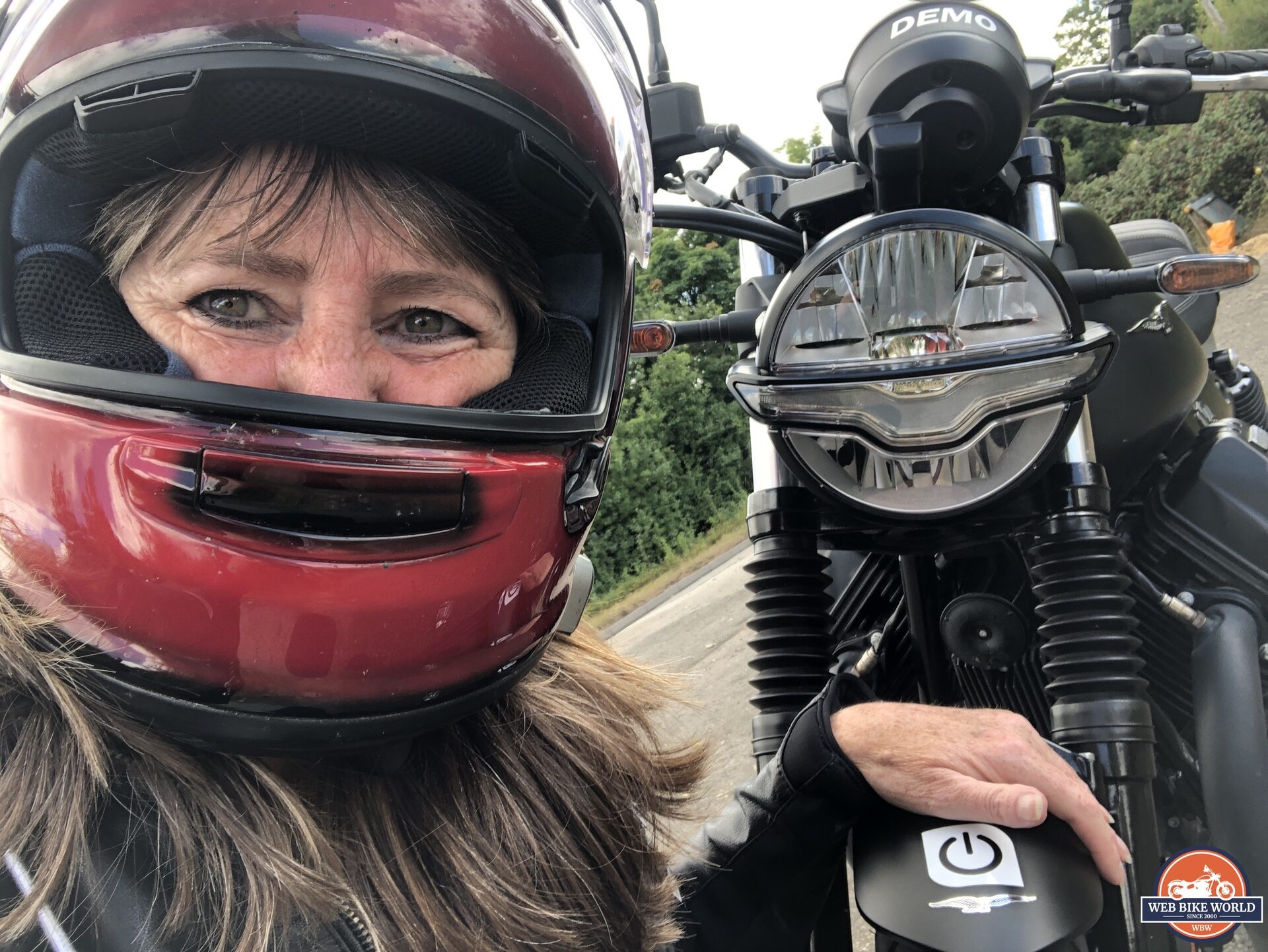 Author grinning underneath helmet next to Moto Guzzi V7 Stone