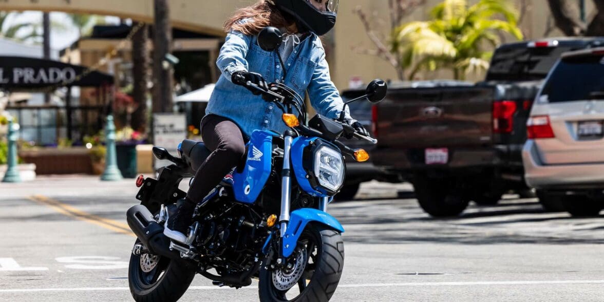 Woman riding small blue Honda Grom on city street