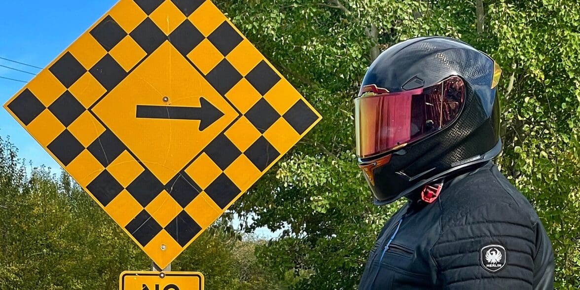 Author wearing Icon Airframe Pro Carbon Helmet and standing next to road sign