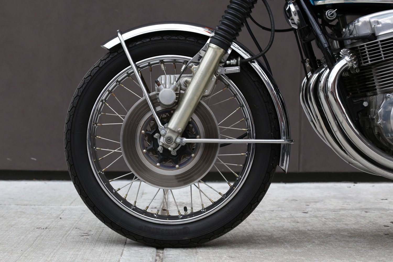 A detail shot of an old Honda CB750 motorcycle's front disc brake