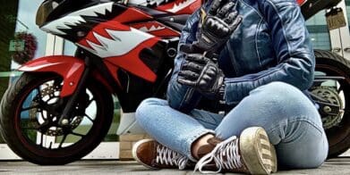 Author sitting cross-legged in front of motorcycle while wearing the Racer USA Women's Pitlane Gloves