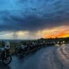 Motorcycles parked under grey clouds at sunset