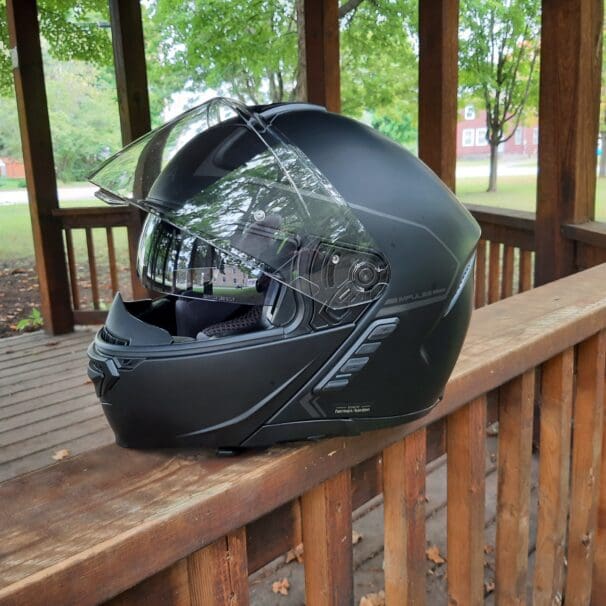 Sena Impulse Modular Helmet sitting on wooden railing