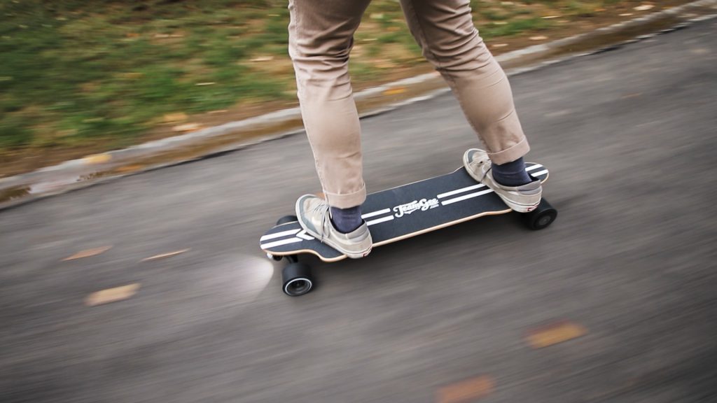 Man riding electric skateboard on road with LED lighting