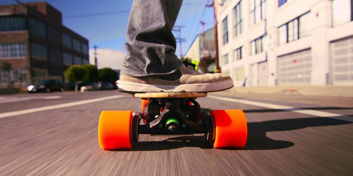 Close up of man riding electric skateboard through town