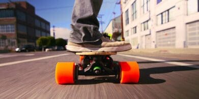 Close up of man riding electric skateboard through town