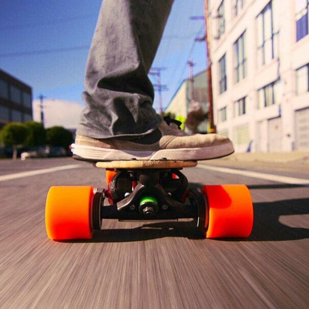 Close up of man riding electric skateboard through town