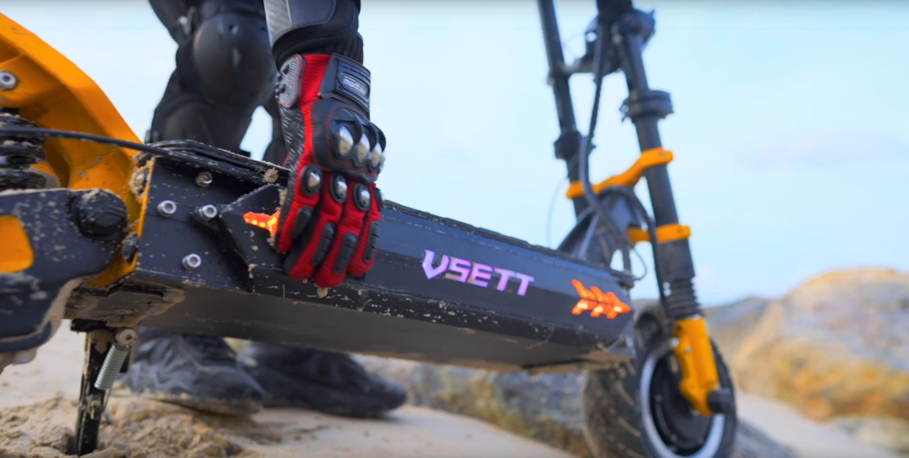 Close up shot of gloved hand holding VSETT 11+ electric scooter deck on sand