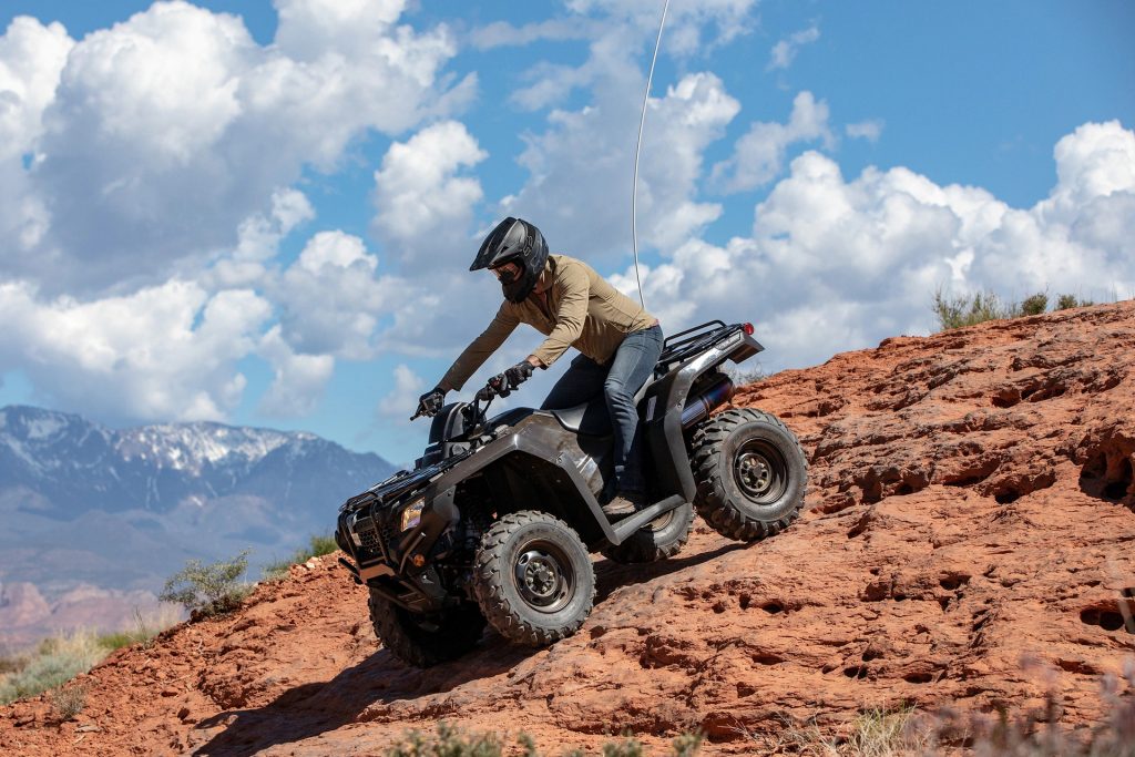 An image of a rider navigating down a rocky surface on a Honda FourTrax Rancher