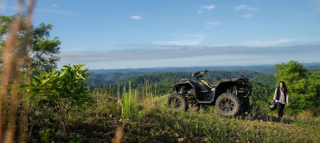 Rider looking at her Sportsman XP 1000 S parked on the top of a hill