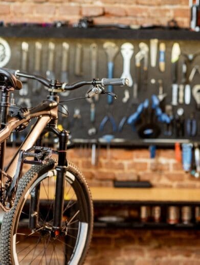 Mountain bike resting on bike stand in workshop with tools on wall