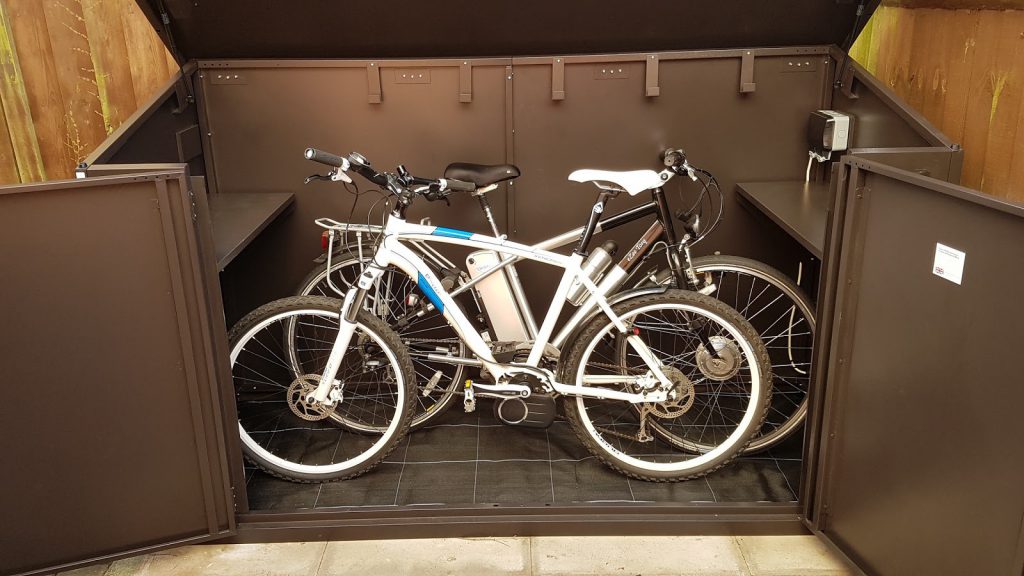 Two electric mountain bikes inside metal bike shed storage and shed