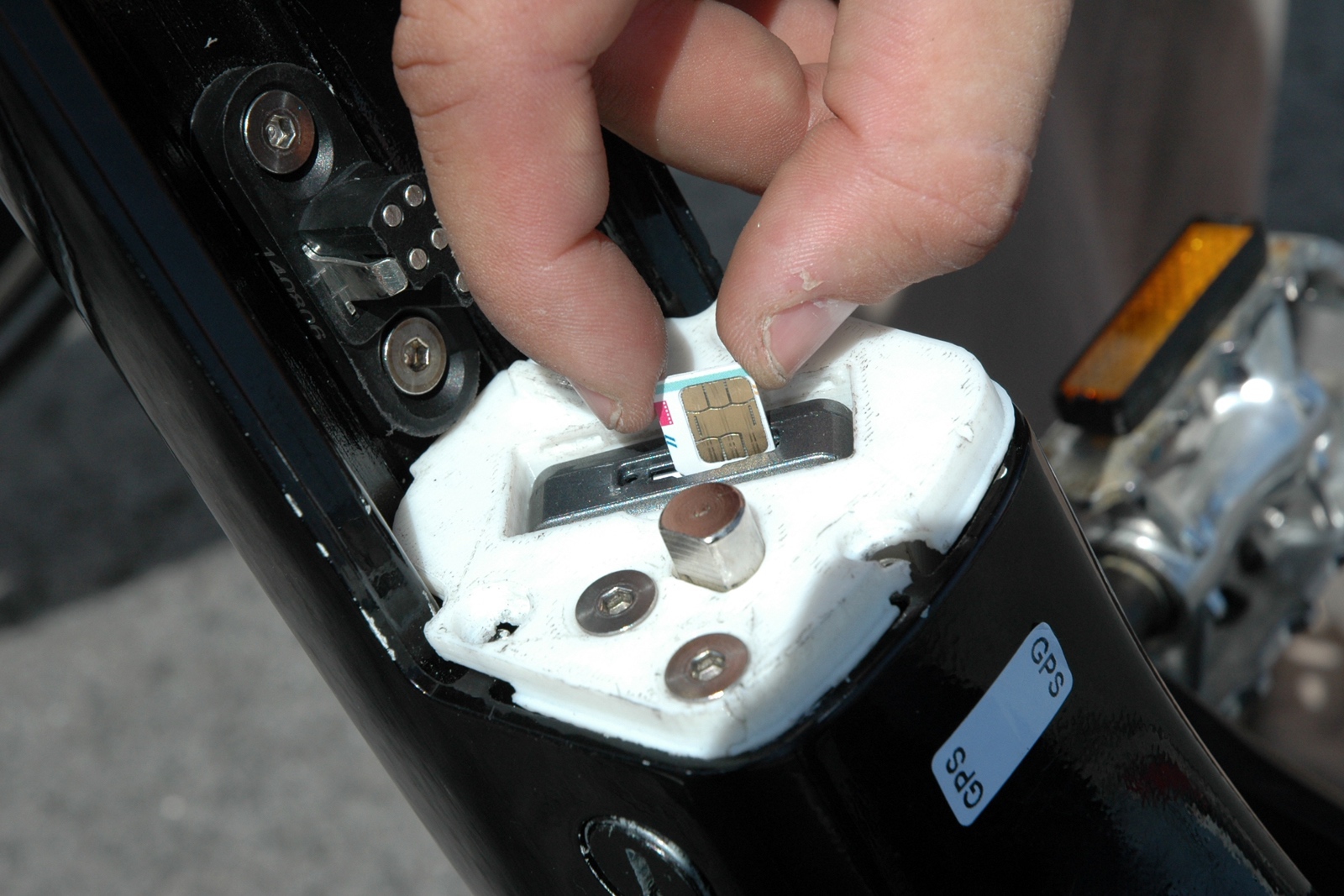 Owner inserting SIM card into GPS tracker for electric bike