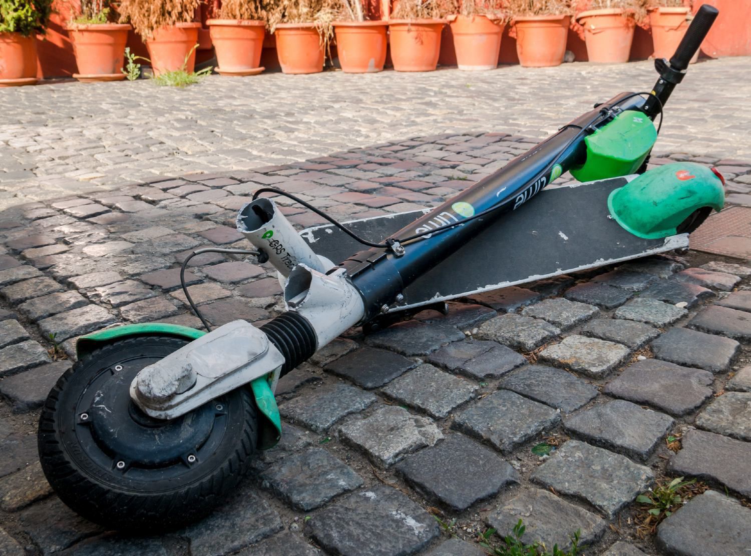Broken electric scooter lays on stone brick floor in two pieces