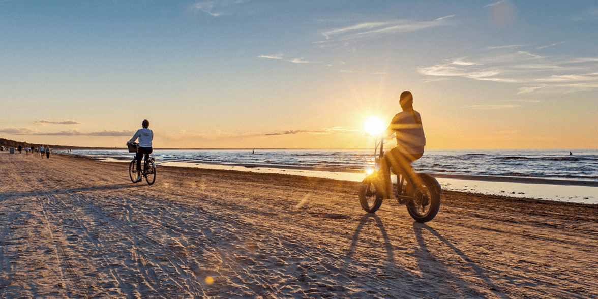 Cyclists riding TurboAnt bikes on a beach