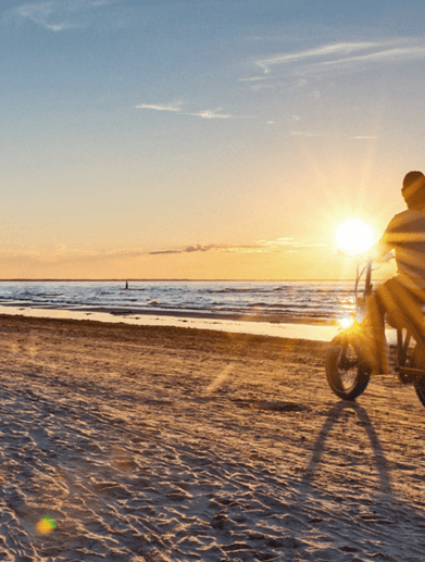 Cyclists riding TurboAnt bikes on a beach