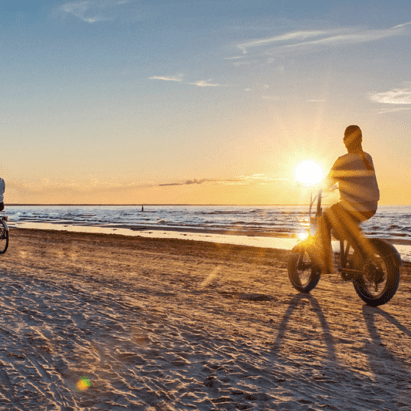 Cyclists riding TurboAnt bikes on a beach