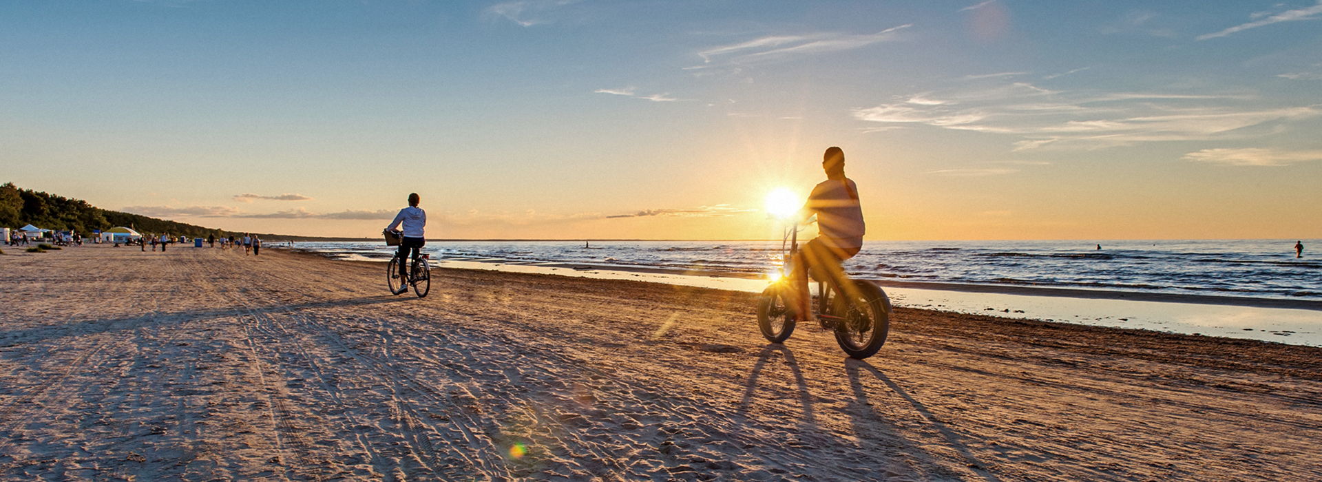 Cyclists riding TurboAnt bikes on a beach