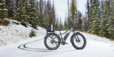 Fat-tire electric mountain bike standing off-road in forest on snow covered path