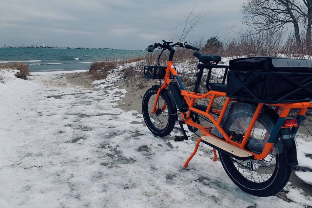 Cargo eBike rests on kickstand near snow-covered and icy beach