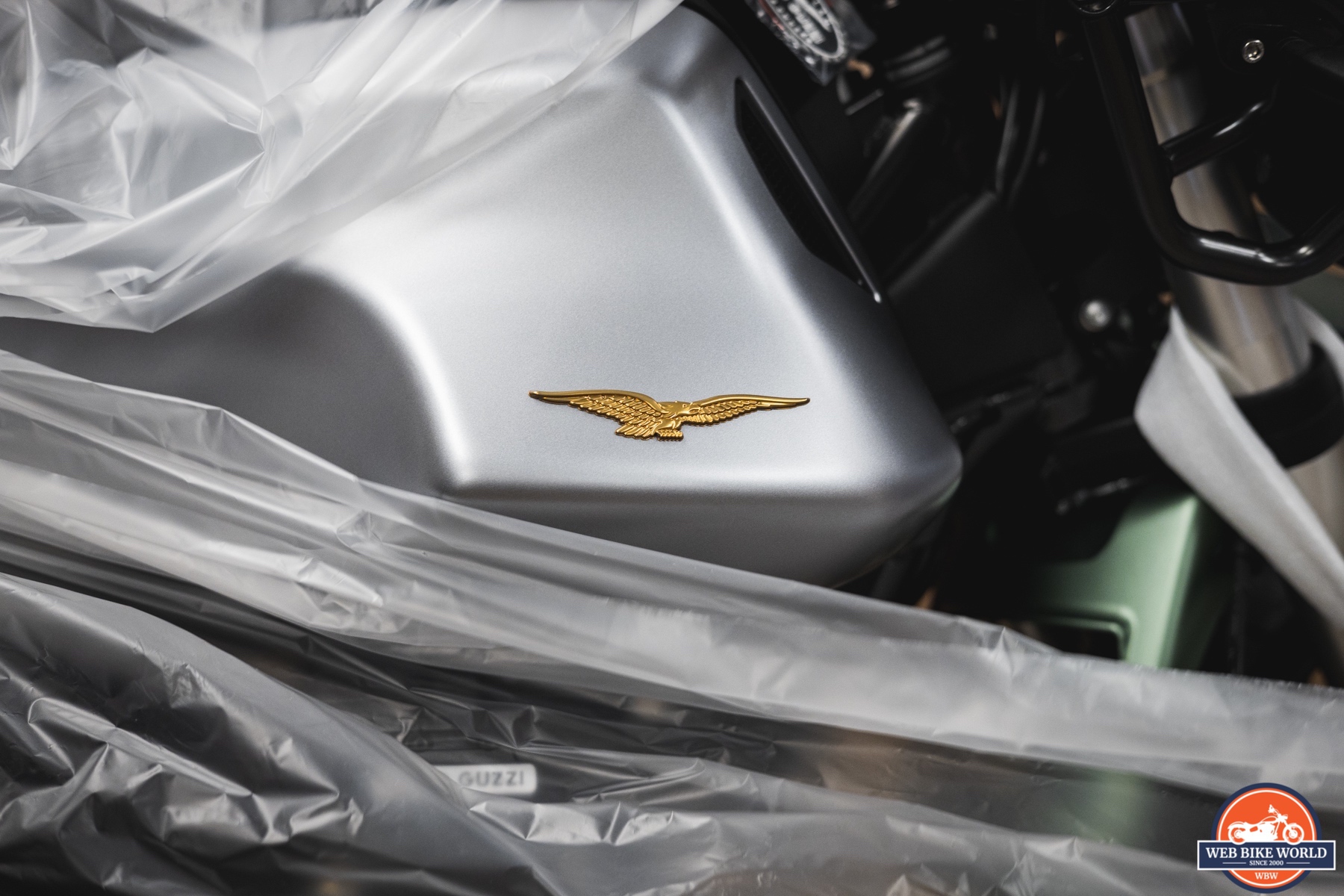 Close up photo of a 2021 Moto Guzzi V85TT Centenario gold eagle-shaped emblem