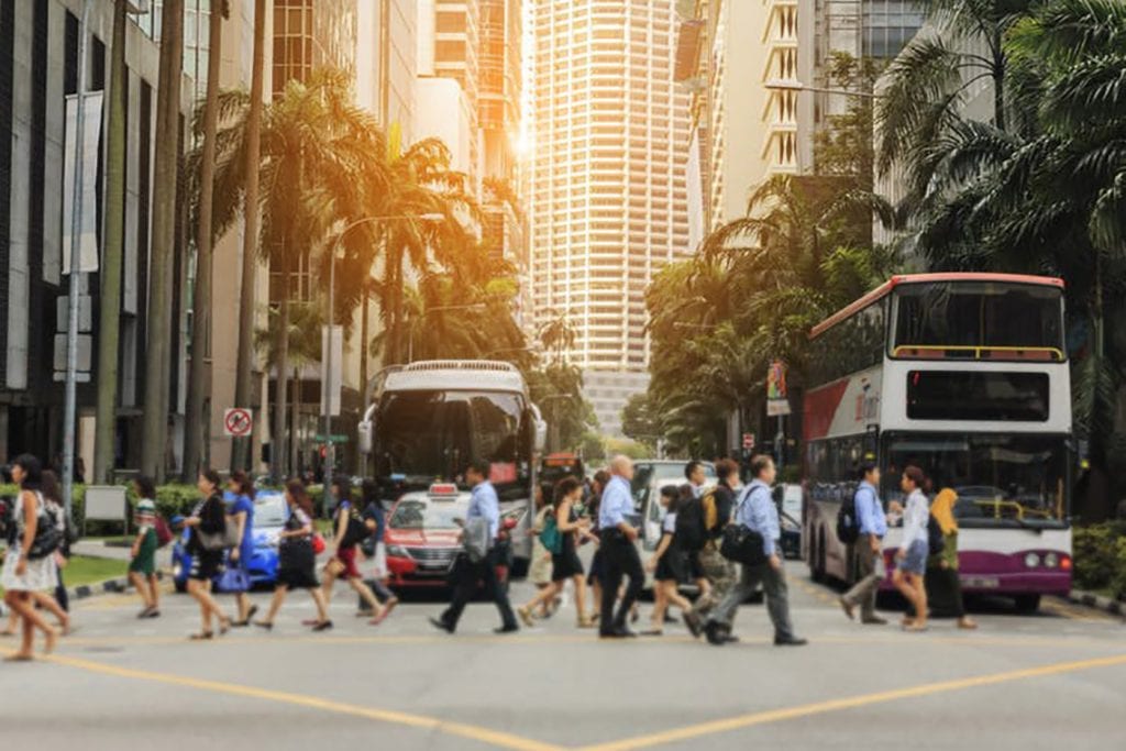 a street in Singapore with the sun behind a building