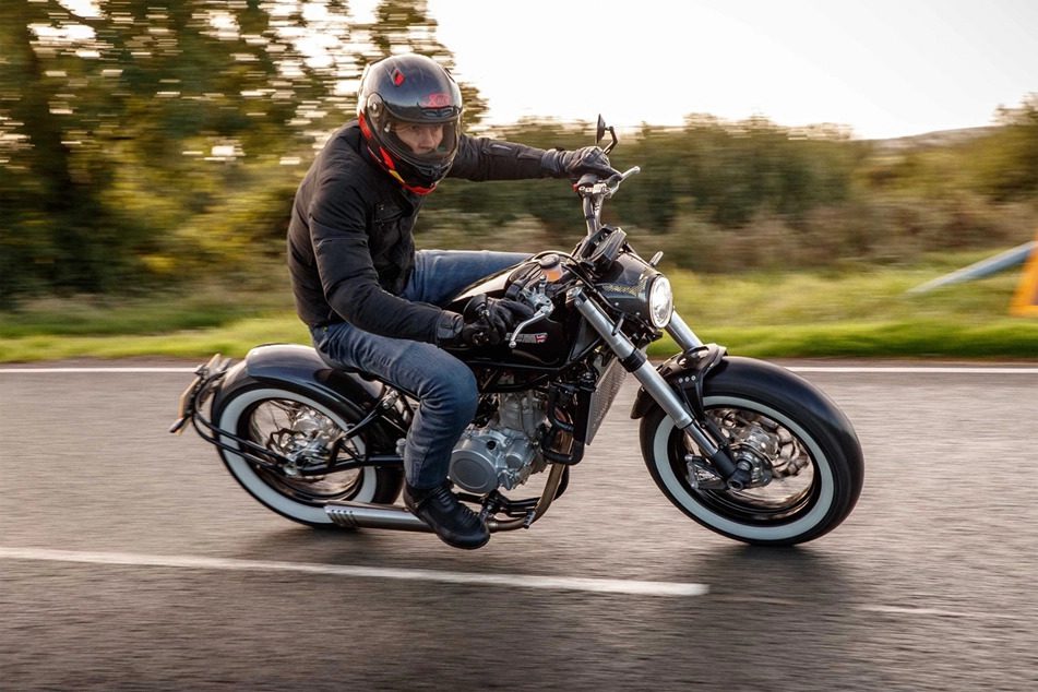 A side view of a rider trying out a CCM Motorcycle on a damp country road