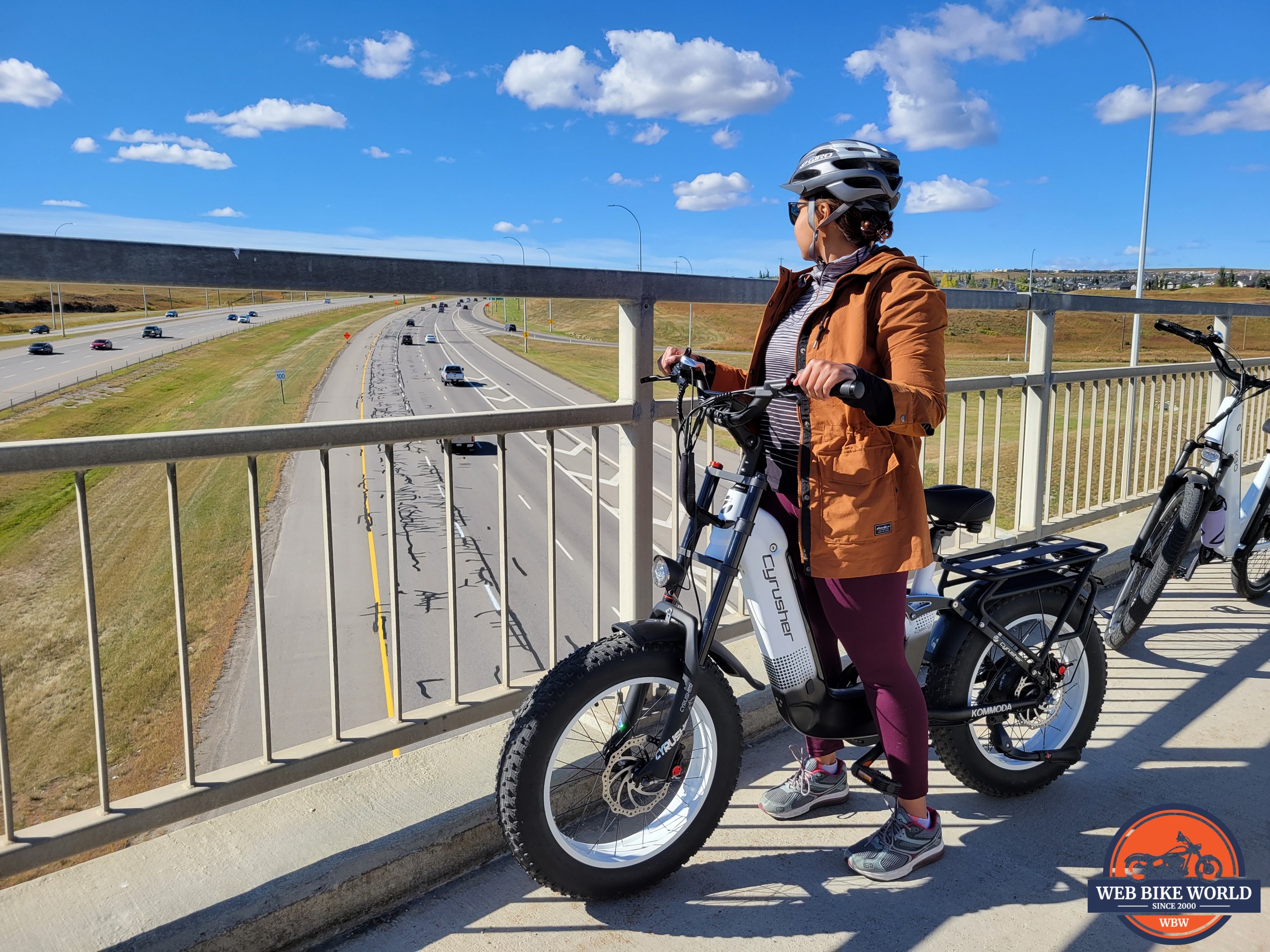 Female rider with ebike on bridge overlooking traffic 