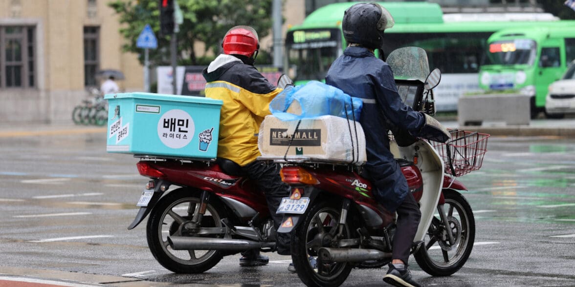 Two motorcyclists waiting for a green light at a Korean intersection. Media sourced from the Korea Herald.