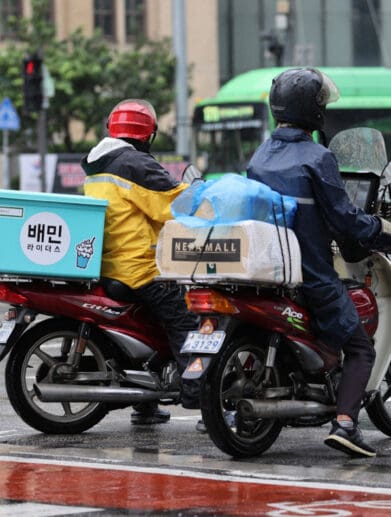 Two motorcyclists waiting for a green light at a Korean intersection. Media sourced from the Korea Herald.